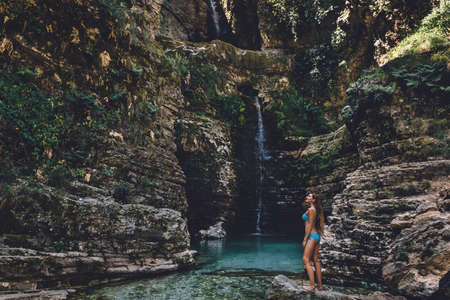 Tanned Woman in Swimsuit Relaxing on Waterfallの写真素材