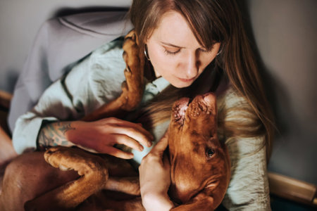 Young Woman Hugging Vizsla Dog at Homeの写真素材
