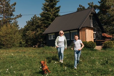 Grandmother and Grandson Playing with Dog Outdoors in Summerの写真素材