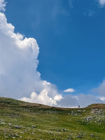 Small Person in large Mountain Landscape with Clouds