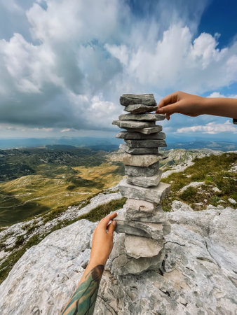 Hands Stacking Stones for Cairn Tower in Mountainsの写真素材