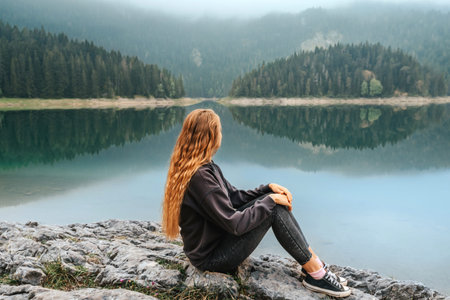 Woman Solo Traveler Sitting by Mountain Lake