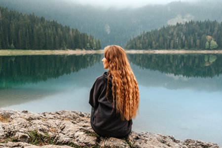 Woman Relaxing and Enjoying Silence by Mountain Lakeの写真素材