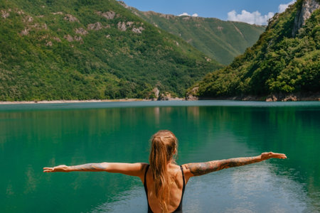 Happy Woman Outstretching Arms in Mountain Lakeの写真素材