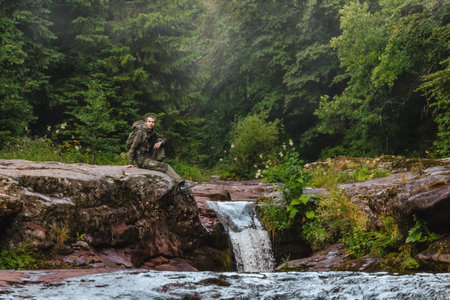 Man Hiker Sitting by River Stream in Forest