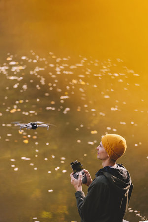 Man Flying Drone against Autumn Lakeの写真素材