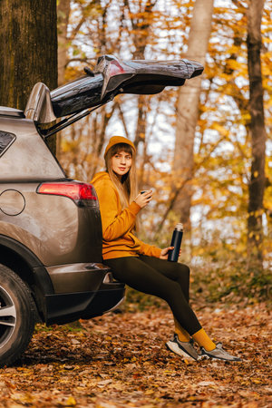Woman Sitting in Car Trunk in Autumn Forest