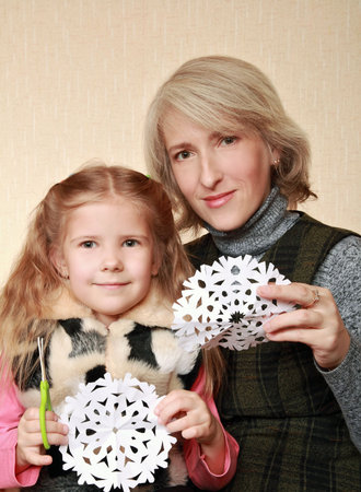 Girl with her mother cut Christmas snowflake の写真素材