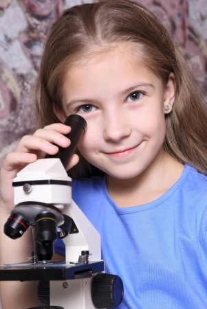 Pleased girl near a microscope  The pleasure of viewing objects at high magnification の写真素材