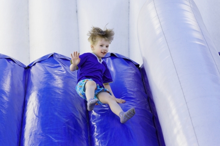 Boy slides down an inflatable slide の写真素材