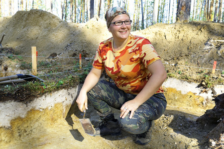 The girl-archaeologist with a trowel in his hand in the excavation の写真素材