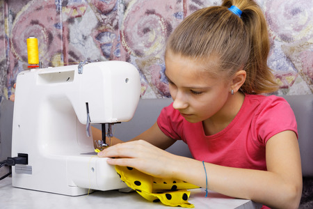 Girl learns to sew on an electric sewing machineの写真素材