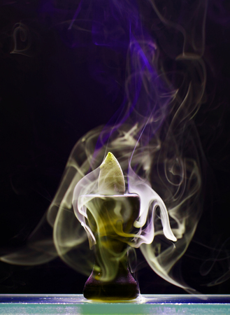 Aromatic cone smoldering in a ceramic stand and emits smoke of different colors and intensityの写真素材