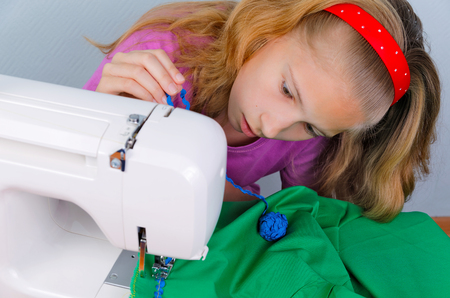 Teen girl frightened by her mistake when sewing on a sewing machineの写真素材