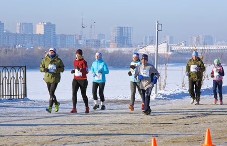 Editorial. Omsk,Russia - January, 07 2018. A group of male and female runners run along the embankment of the Irtysh River during 27 th Christmas winter half marathon in Naberezhnaya Tukhachevskogo streetのeditorial素材