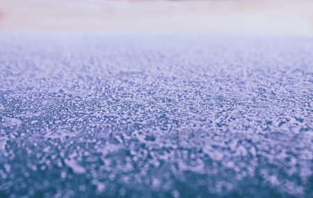 Background: smooth metallic surface covered with thick frost and illuminated by dim morning lightの写真素材