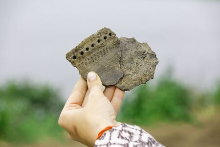 Pieces of ancient clay vessel in the hand of an archaeologistの写真素材