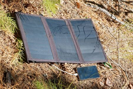 Collapsible solar panel charges a smartphoneの写真素材