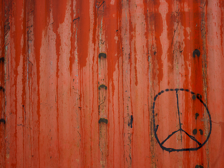 Sign pacifist painted in black on a red fenceの写真素材