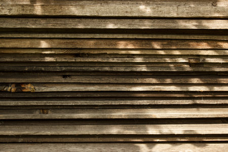 Stack of non-planed pine boards with sunlight reflections