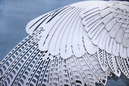 The carved wing of a wooden bird lies on a blue tableの写真素材