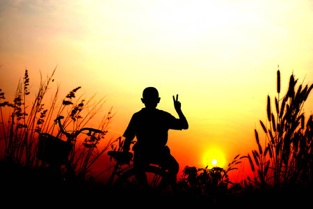 Silhouette of people Image of sporty on bicycles outdoors against sunset, A boy sitting on a bicycle. Silhouette of a bike and boy. Sunset vibrant orangeの写真素材