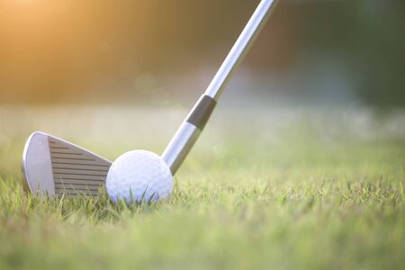 Golf clubs and golf balls on a green lawn in a beautiful golf course with morning sunshine.Ready for golf in the first short.Sports that people around the world play during the holidays for health.の写真素材