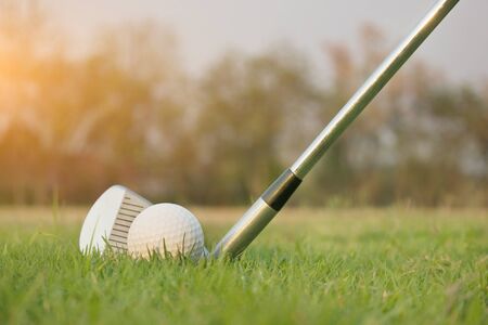 Golf clubs and golf balls on a green lawn in a beautiful golf course with morning sunshine.Ready for golf in the first short.Sports that people around the world play during the holidays for health.の写真素材