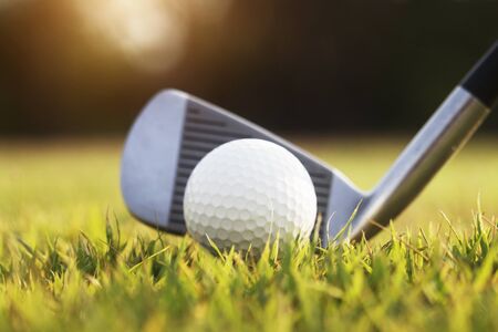 Golf clubs and golf balls on a green lawn in a beautiful golf course with morning sunshine.Ready for golf in the first short.Sports that people around the world play during the holidays for health.の写真素材