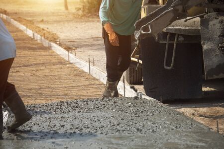 Workers pouring concrete with a cement mixer truck. Road construction or general surface repairの写真素材