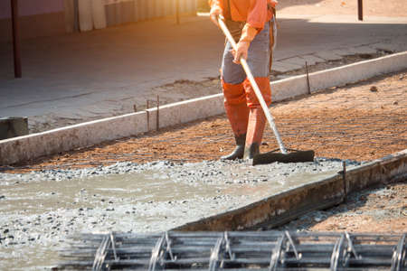 Workers are using tools to smooth the concrete floor. Road construction or general surface repairの写真素材