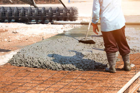 Workers are using tools to smooth the concrete floor. Road construction or general surface repair