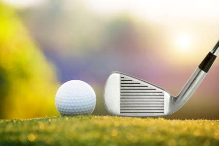 Golf clubs and golf balls on a green lawn in a beautiful golf course with morning sunshine.Ready for golf in the first short.Sports that people around the world play during the holidays for health.の写真素材