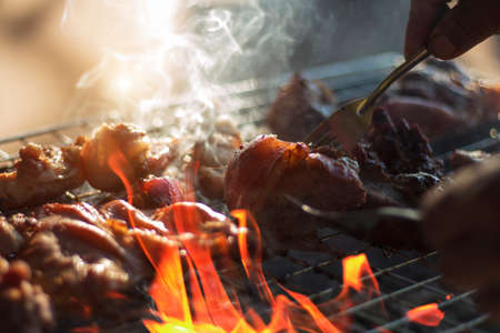 Steak on the grill with flames and smoke. Outdoor cooking using a wood charcoal stove. Popular BBQ...