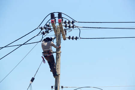Electrician is installing an electrical wiring system on a power pole. Engineer working at height...