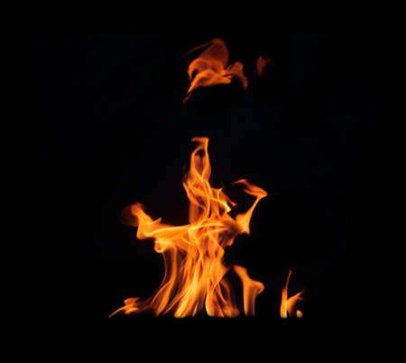 Close up burning flames on black background for graphic design or wallpaper. Red and yellow, heat energy igniting fuel during night. Abstract shaped fire used for cooking.の写真素材