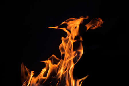 Close up burning flames on black background for graphic design or wallpaper. Red and yellow, heat energy igniting fuel during night. Abstract shaped fire used for cooking.の写真素材