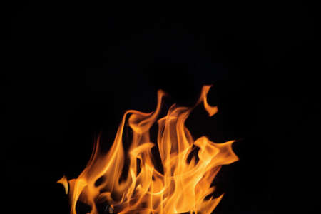 Close up burning flames on black background for graphic design or wallpaper. Red and yellow, heat energy igniting fuel during night. Abstract shaped fire used for cooking.の写真素材