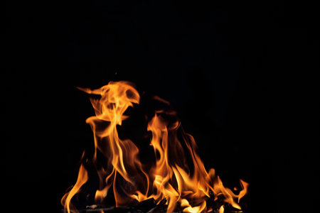 Close up burning flames on black background for graphic design or wallpaper. Red and yellow, heat energy igniting fuel during night. Abstract shaped fire used for cooking.の写真素材