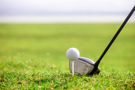Golf clubs and golf balls on a green lawn in a beautiful golf course with morning sunshine. Ready to play in the first short. Sports that people around the world play during the holidays for health.の写真素材