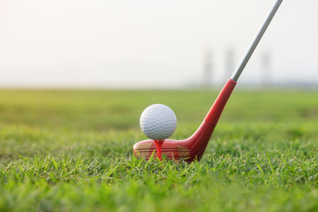 Golf clubs and golf balls on a green lawn in a beautiful golf course with morning sunshine. Ready to play in the first short. Sports that people around the world play during the holidays for health.の写真素材