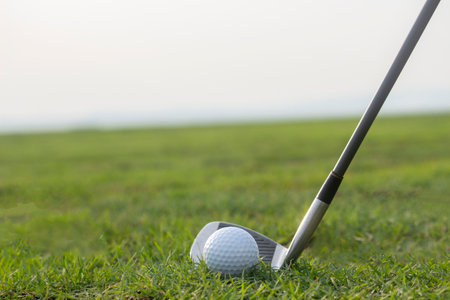 Golf clubs and golf balls on a green lawn in a beautiful golf course with morning sunshine. Ready to play in the first short. Sports that people around the world play during the holidays for health.の写真素材