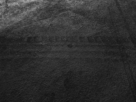 Close up black tire marks on cement floor. Abstract concrete texture in vintage style. Dark background for graphic design or wallpaper. Stains on the road surface caused by the wheels of the car.の写真素材