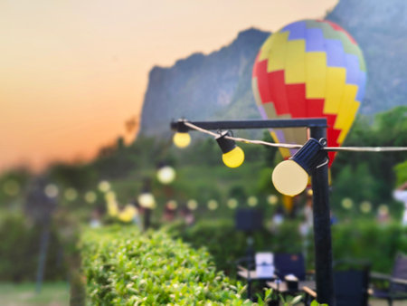 Glowing string lights hang along a garden path at sunset, with soft bokeh in the blurred background. Evening lights with a happy festival or celebration atmosphereの写真素材