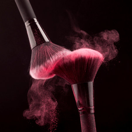 Makeup brush with pink powder explosion on black background, beauty conceptの写真素材
