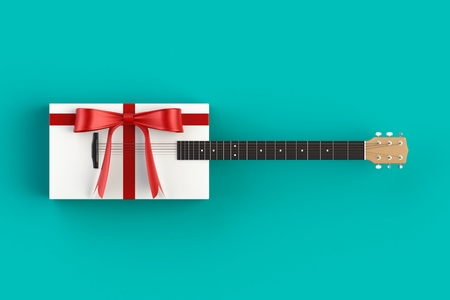 Christmas and New Year's Day, Gift box with red ribbon with guitar on blue table background, 3d renderingの写真素材