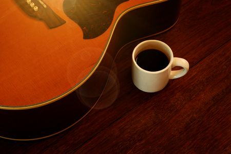 cup of coffee and acoustic guitar on wooden floorの写真素材