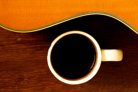 cup of coffee and acoustic guitar on wooden floorの写真素材