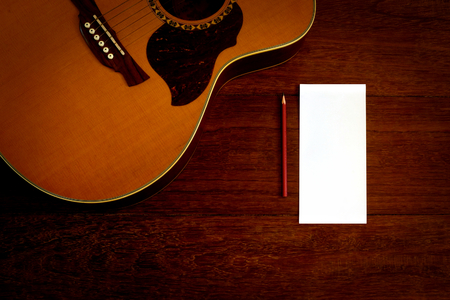 note paper and pencil with acoustic guitar on wooden floorの写真素材