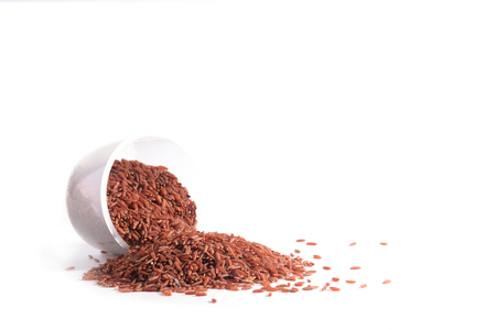 Pile of brown rice  with white plastic cup on white background.の写真素材